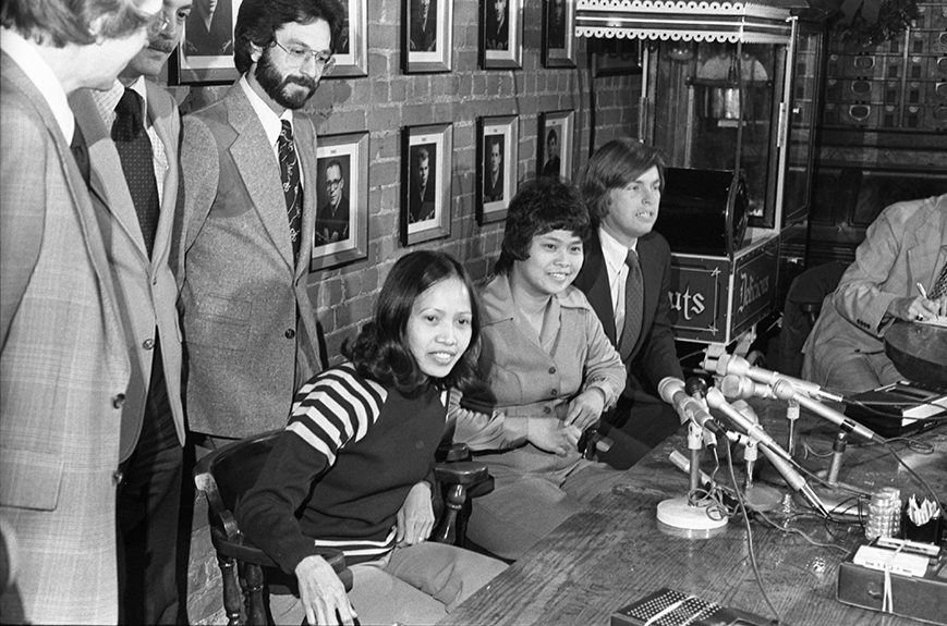Defendants Leonora Perez and Filipina Narciso smiling and sitting at a press conference table.